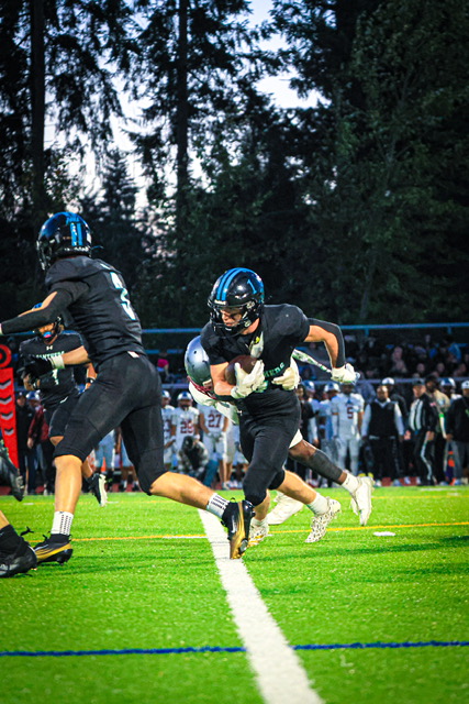 Colt Miller cradles the ball and cuts toward the sideline during a night game as a teammate leads the way